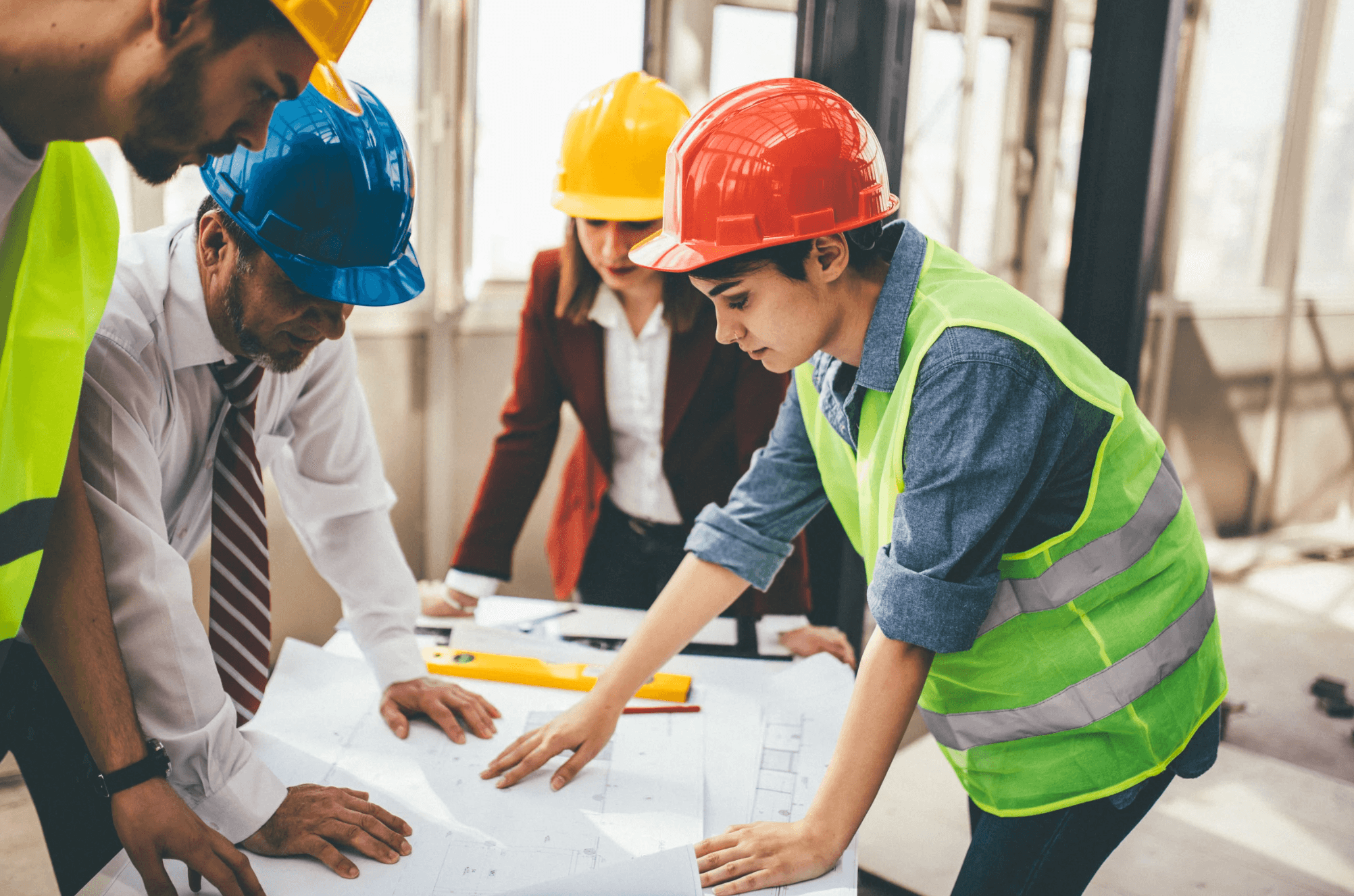 Project team in hard hats reviewing construction documents around a table